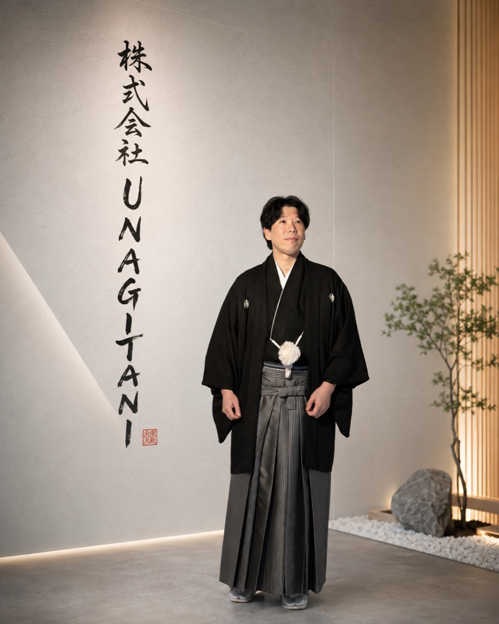 株式会社UNAGITANIの壁面ロゴ前に立つ代表取締役 森 佑紀